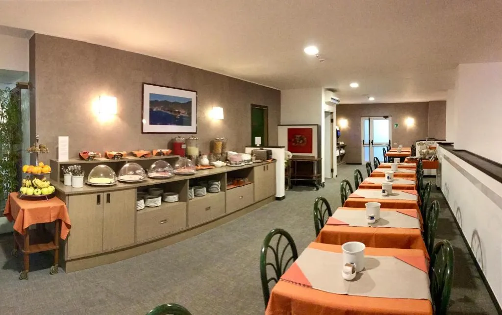 Sala colazione con buffet, tavoli apparecchiati con tovaglie arancioni e sedie