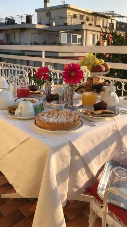 Tavolo per colazione su terrazza con crostata, dolci, frutta e succhi al tramonto