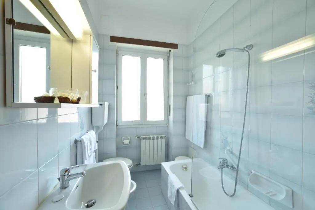 Bagno luminoso con vasca, lavabo, specchio e finestra