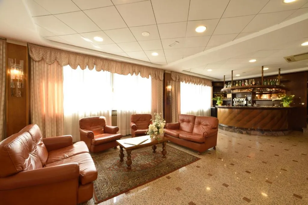 Hall dell'hotel con divani in pelle, tavolino e bar sullo sfondo