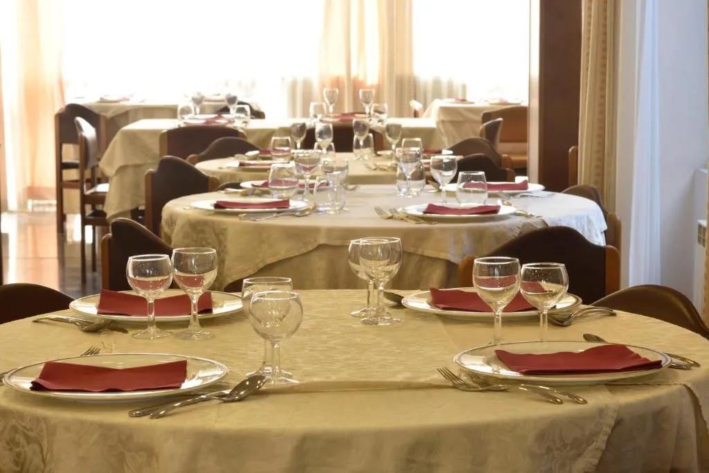 Sala ristorante con tavoli rotondi apparecchiati con tovaglie e tovaglioli rossi