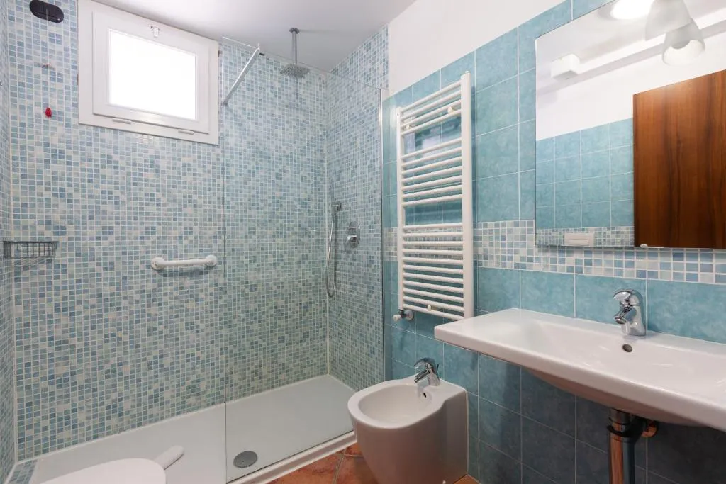 Bagno con doccia, mosaico azzurro, lavabo, bidet e scaldasalviette