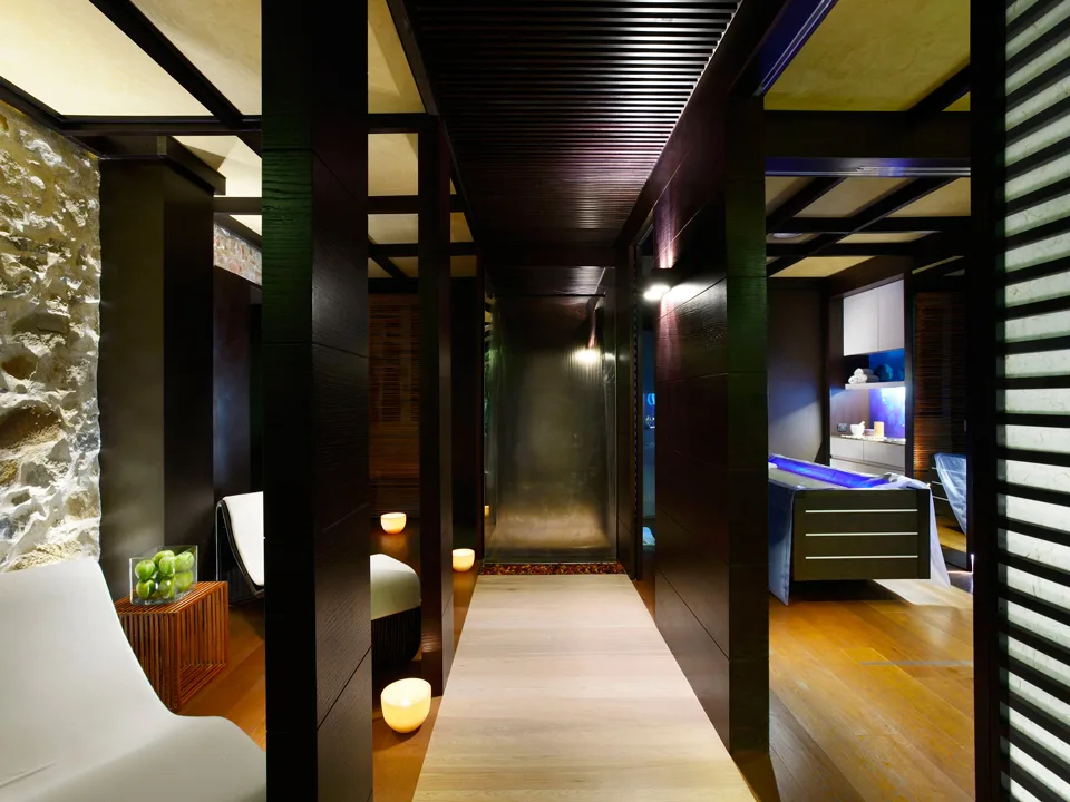Area relax della spa con legno scuro, pareti in pietra e candele soffuse