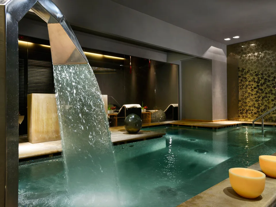 Piscina interna della spa con cascata d'acqua e illuminazione soffusa