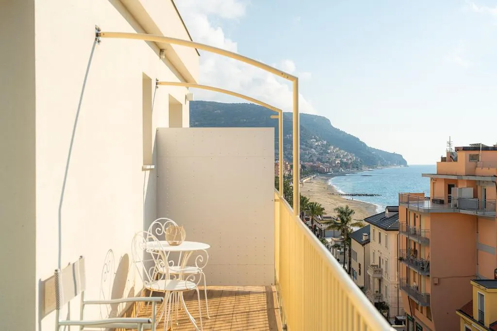 Balcone con tavolino e sedie bianche affacciato sul mare e sulla spiaggia