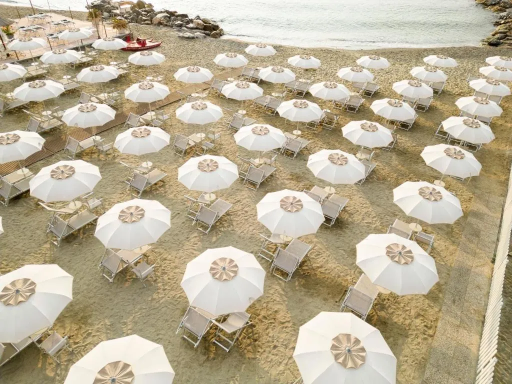 Spiaggia con file di ombrelloni bianchi e lettini vista mare