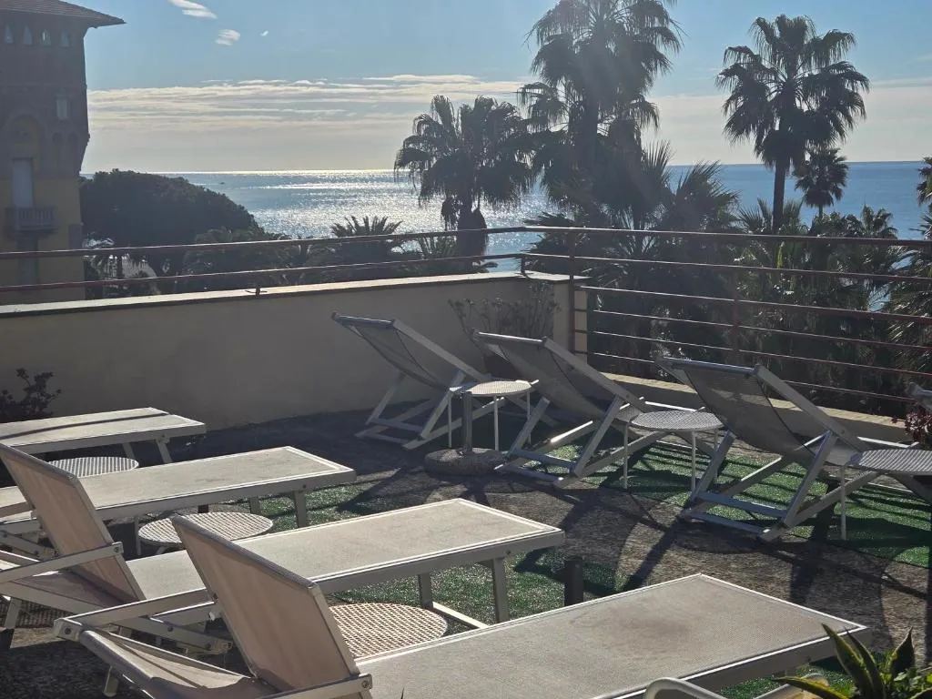 Terrazza con lettini prendisole e vista sul mare tra palme