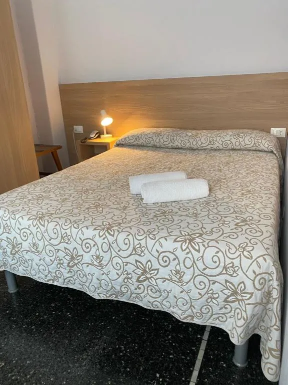 Letto matrimoniale con copriletto floreale e asciugamani arrotolati