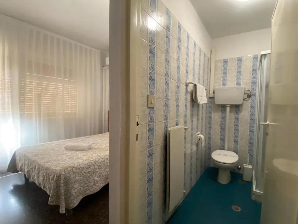 Camera con letto matrimoniale e bagno con piastrelle azzurre, WC e doccia
