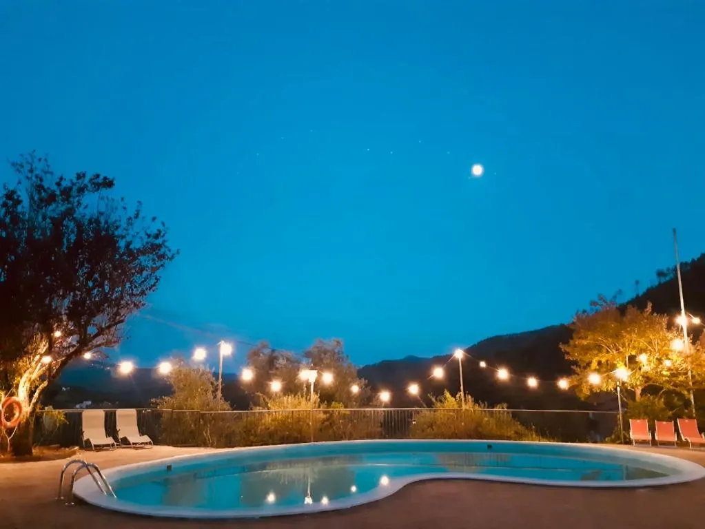 Piscina illuminata al crepuscolo con luci decorative e luna nel cielo blu