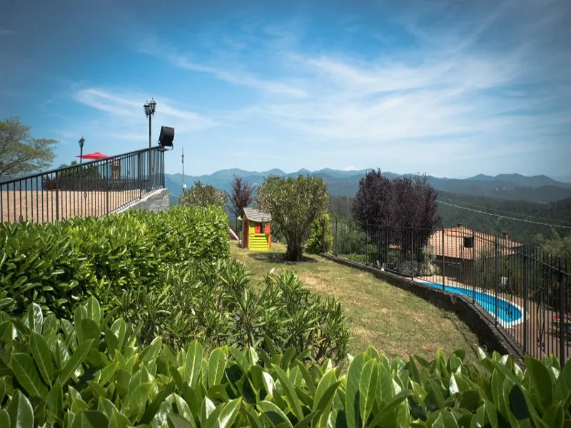 Giardino con siepi e piscina sullo sfondo affacciato sulle colline boscose