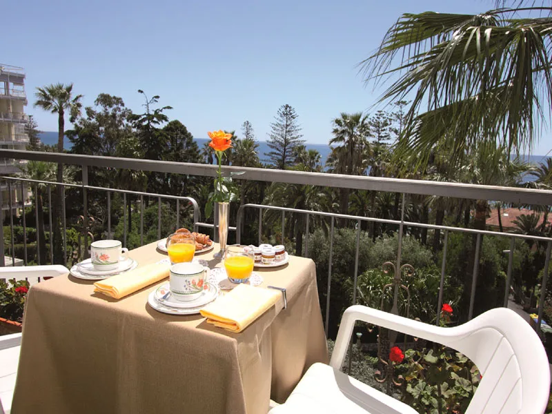 Colazione servita su un balcone con vista sul mare, le palme e il giardino