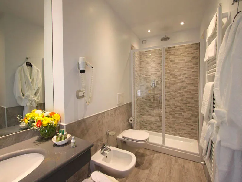 Bagno moderno con doccia ampia, lavabo, bidet e accappatoio appeso