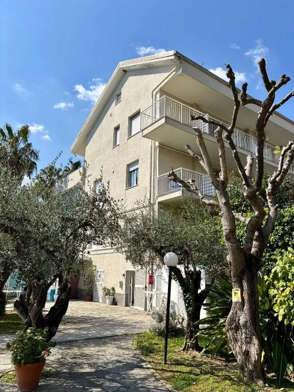 Esterno dell'edificio con balconi, ulivi e giardino curato