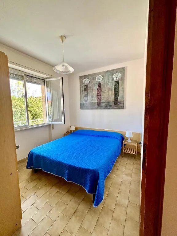 Camera da letto matrimoniale con copriletto blu e finestra sul verde