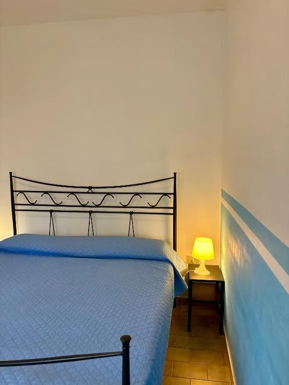 Camera da letto matrimoniale con copriletto azzurro e dettaglio decorativo alla parete