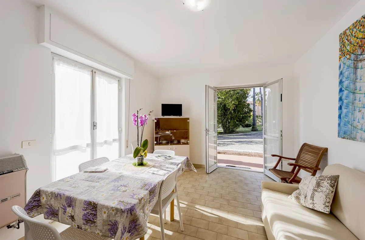 Soggiorno luminoso con tavolo da pranzo, divano e porta-finestra sul giardino