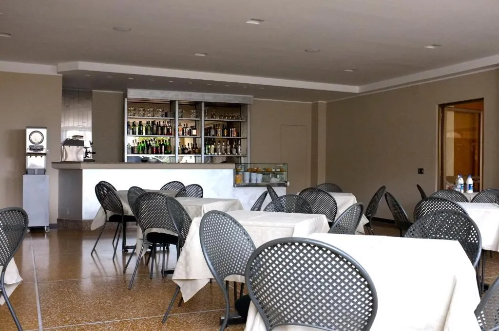Sala bar e colazione con tavoli apparecchiati e bancone con bottiglie