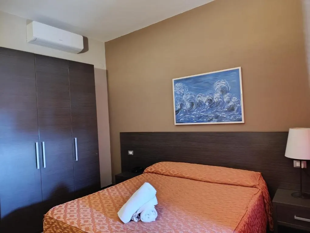 Camera con letto matrimoniale, armadio scuro e quadro raffigurante onde del mare