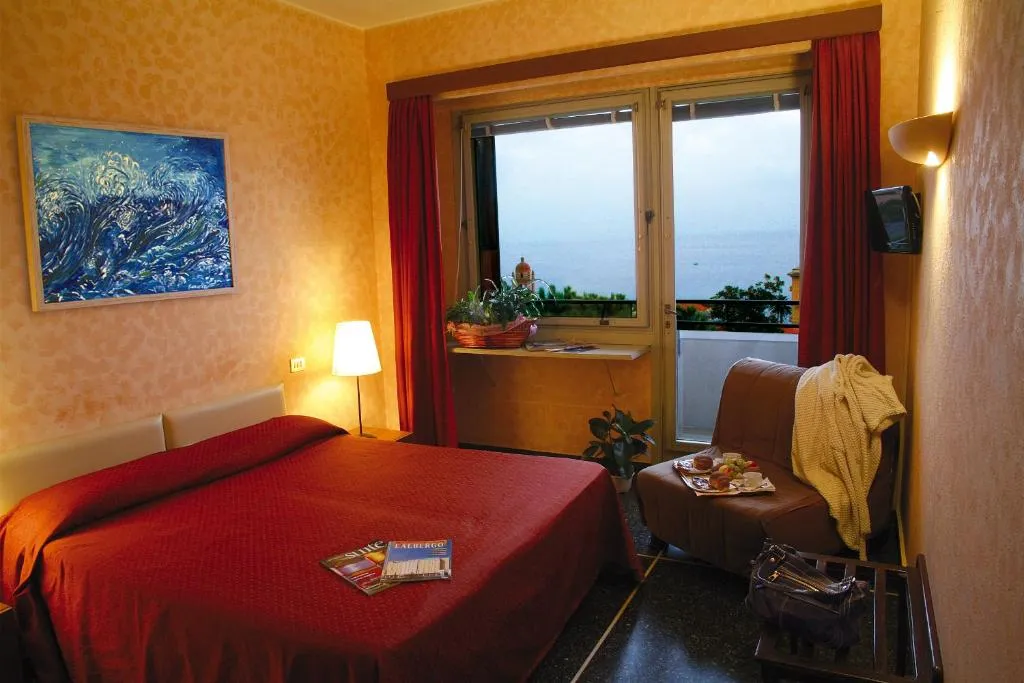 Camera con letto matrimoniale, poltrona e finestra con vista sul mare