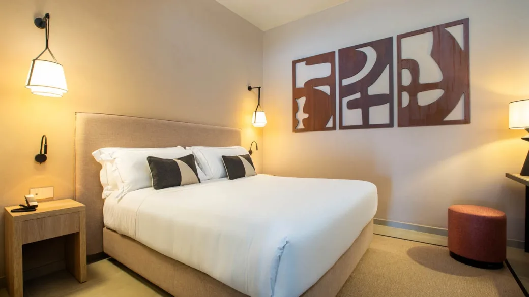 Camera matrimoniale con letto bianco, applique e decorazioni in legno alle pareti