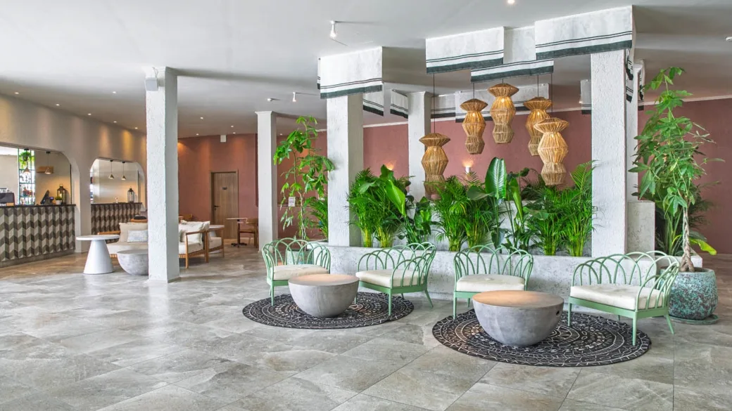 Lobby dell'hotel con piante verdi, sedute, lampade in rattan e reception
