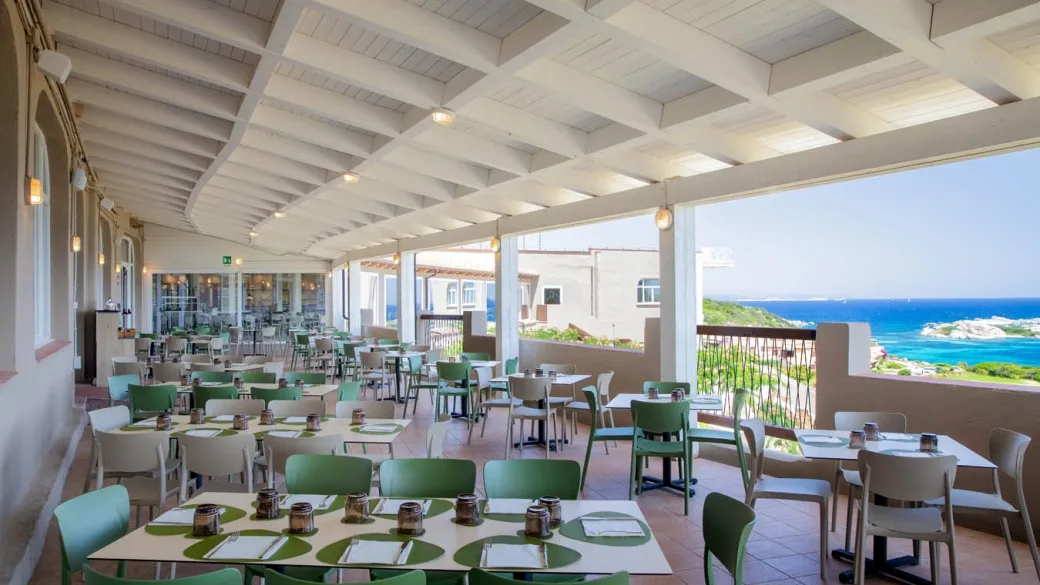 Ristorante con terrazza coperta, tavoli verdi e vista sul mare