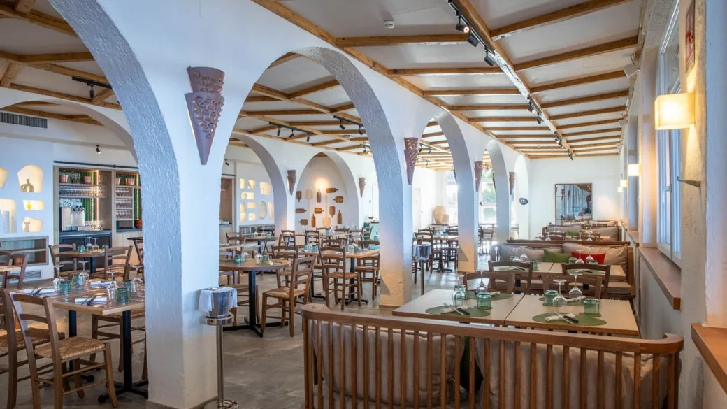 Sala ristorante con archi bianchi, travi in legno e tavoli apparecchiati