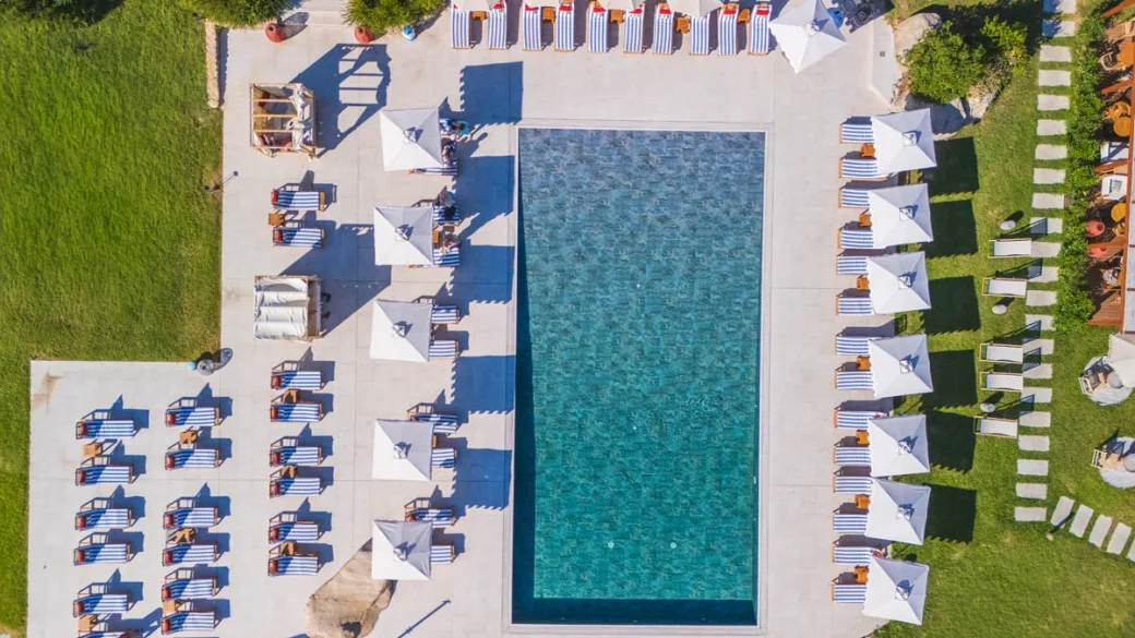 Vista dall'alto della piscina rettangolare con lettini e ombrelloni disposti ai lati