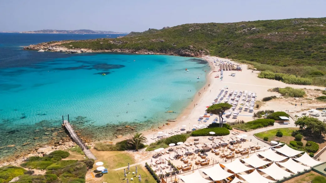 Veduta aerea della spiaggia con mare turchese, sabbia bianca e ombrelloni