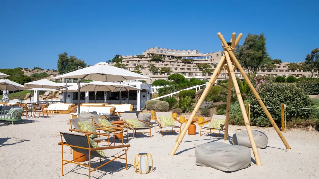 Area relax sulla spiaggia con poltrone, ombrelloni e resort sullo sfondo