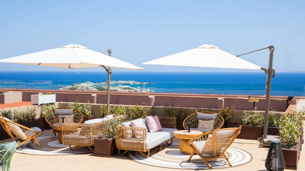 Terrazza panoramica con poltrone in rattan, ombrelloni e vista sul mare