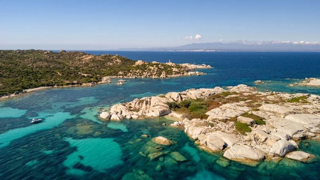 Veduta aerea della costa con scogli, mare cristallino e barca all'ancora