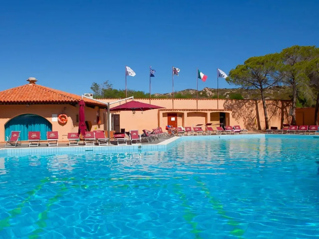 Piscina del resort con lettini, ombrelloni e bandiere