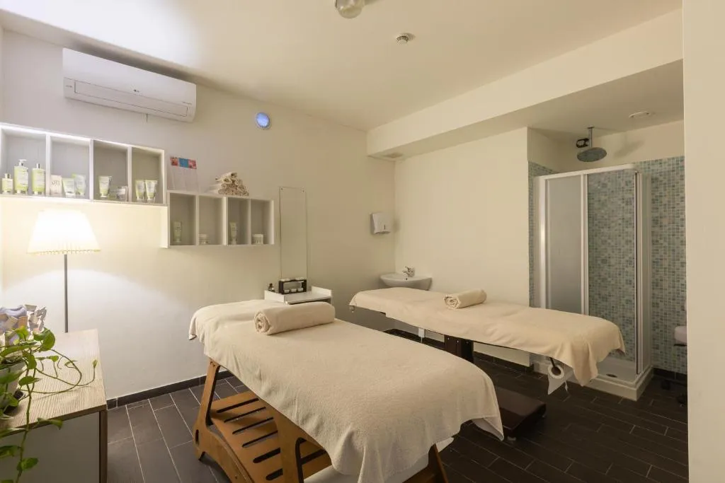 Sala massaggi della spa con due lettini, prodotti e doccia