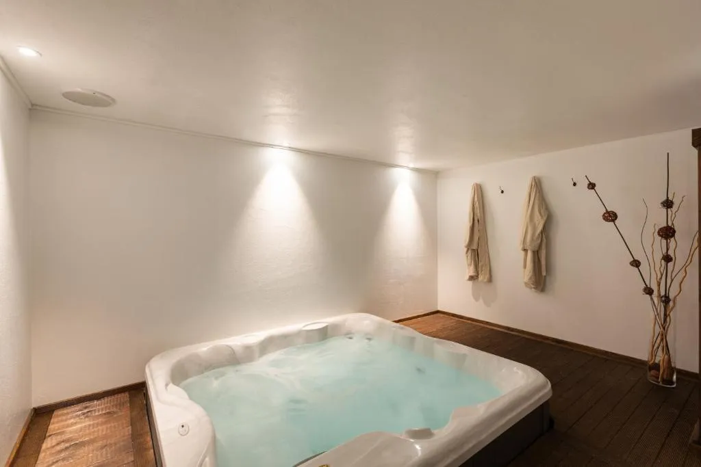 Vasca idromassaggio in ambiente minimal con accappatoi alla parete