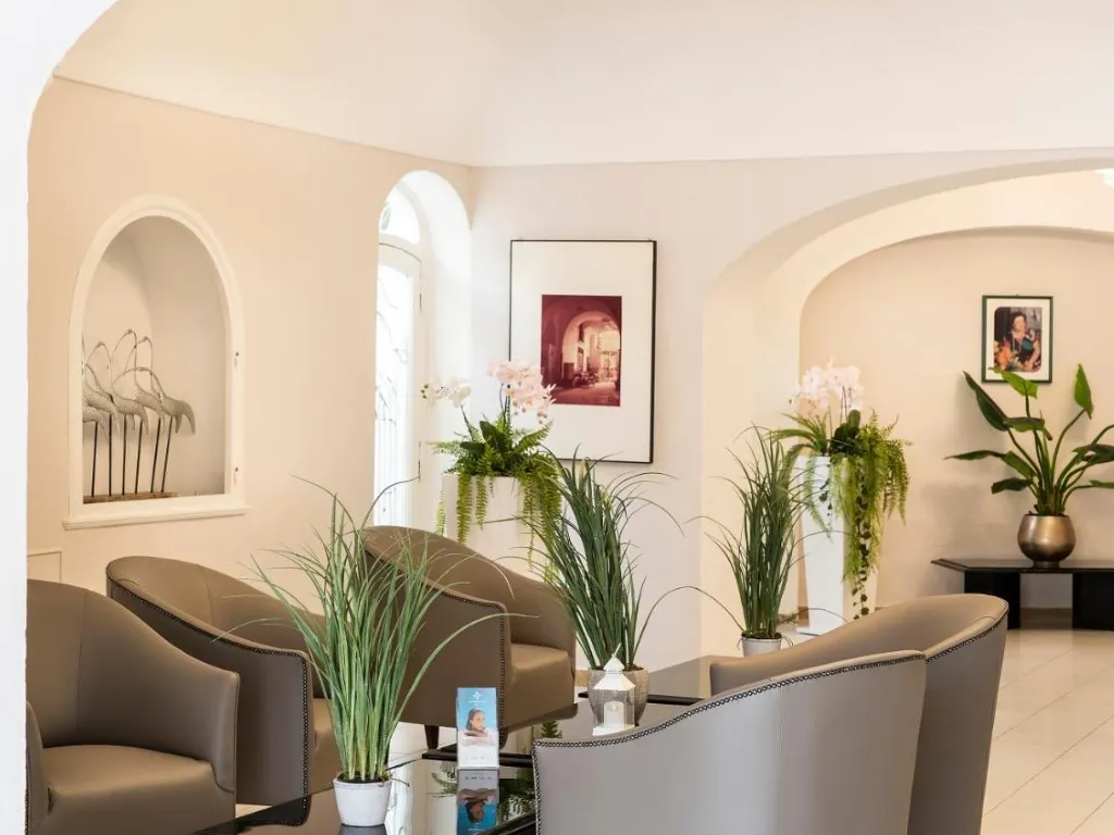 Salottino della hall con poltrone, piante verdi e orchidee